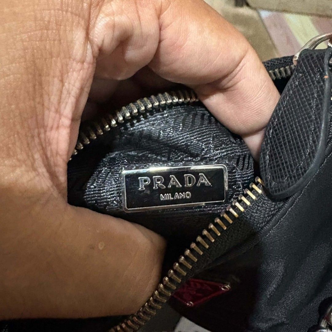 Prada Re-Edition 2005 Nylon Black Shoulder Bag (Category: Sling Bags) located in Carmen. Submitted by ar_thrift00 (Listing ID 1470560777, Image 2). Description: - Prada Re-Edition 2005 shoulder bag in classic black nylon - Features sleek silver-tone hardware and a stylish metal chain accent - Includes an adjustable woven strap with a small detachable pouch - Iconic Prada Milano logo plaque on the front and interior lining - Secure zipper closure 