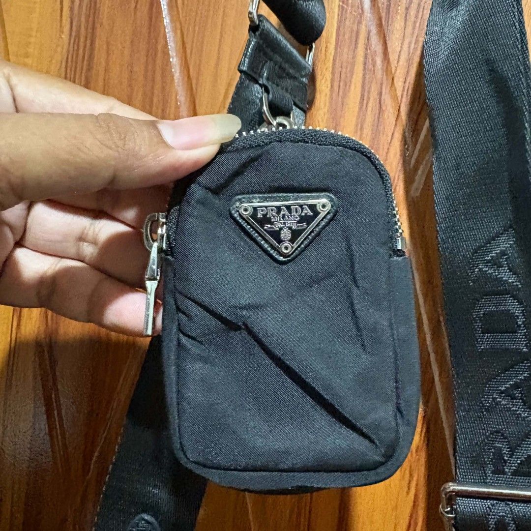 Prada Re-Edition 2005 Nylon Black Shoulder Bag (Category: Sling Bags) located in Carmen. Submitted by ar_thrift00 (Listing ID 1470560777, Image 3). Description: - Prada Re-Edition 2005 shoulder bag in classic black nylon - Features sleek silver-tone hardware and a stylish metal chain accent - Includes an adjustable woven strap with a small detachable pouch - Iconic Prada Milano logo plaque on the front and interior lining - Secure zipper closure 