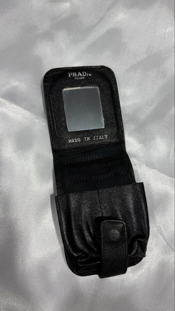 Prada Saffiano Leather Makeup Case Mirror Pouch (Category: Luxury Bags & Wallets) located in Baguio. Submitted by zeemoda01 (Listing ID 1470591965, Image 2). Description: - Authentic Prada lipstick or essentials case - Crafted from durable black Saffiano leather - Iconic enamel triangle logo plaque on the front - Secure flap closure with snap button - Built-in interior mirror with Prada Milano gold stamp - Made in Italy - Compact, structured desi