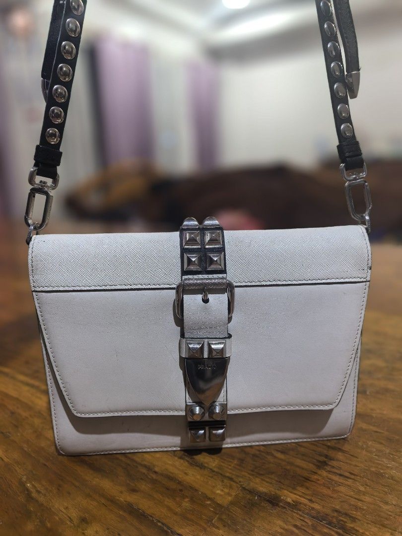 Prada White Leather Studded Shoulder Bag (Category: Luxury Bags & Wallets) located in Cagayan de Oro. Submitted by tommygurl1218 (Listing ID 1470737797, Image 1). Description: White leather shoulder bag by Prada. Distinctive metal pyramid studs along the front closure strap and adjustable black leather strap. Silver-tone hardware throughout. Interior zipped pocket with Prada logo lining and Made in Italy stamp. Minor scuffs and signs of wear on t