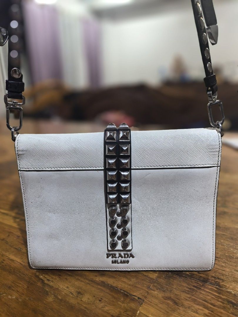 Prada White Leather Studded Shoulder Bag (Category: Luxury Bags & Wallets) located in Cagayan de Oro. Submitted by tommygurl1218 (Listing ID 1470737797, Image 2). Description: White leather shoulder bag by Prada. Distinctive metal pyramid studs along the front closure strap and adjustable black leather strap. Silver-tone hardware throughout. Interior zipped pocket with Prada logo lining and Made in Italy stamp. Minor scuffs and signs of wear on t