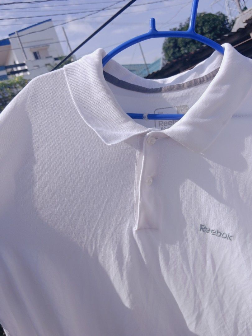 Reebok white polo shirt (Category: Tshirts & Polo Shirts ) located in Gapan. Submitted by athenascarlet (Listing ID 1470597862, Image 1). Description: - Brand: Reebok - Color: Classic White - Details: Collar neckline with 2 white buttons, small gray embroidered logo on chest, ribbed collar with gray inner piping - Material: Comfortable, breathable fabric - Condition: Excellent / Like new - Style: Versatile everyday staple piece.