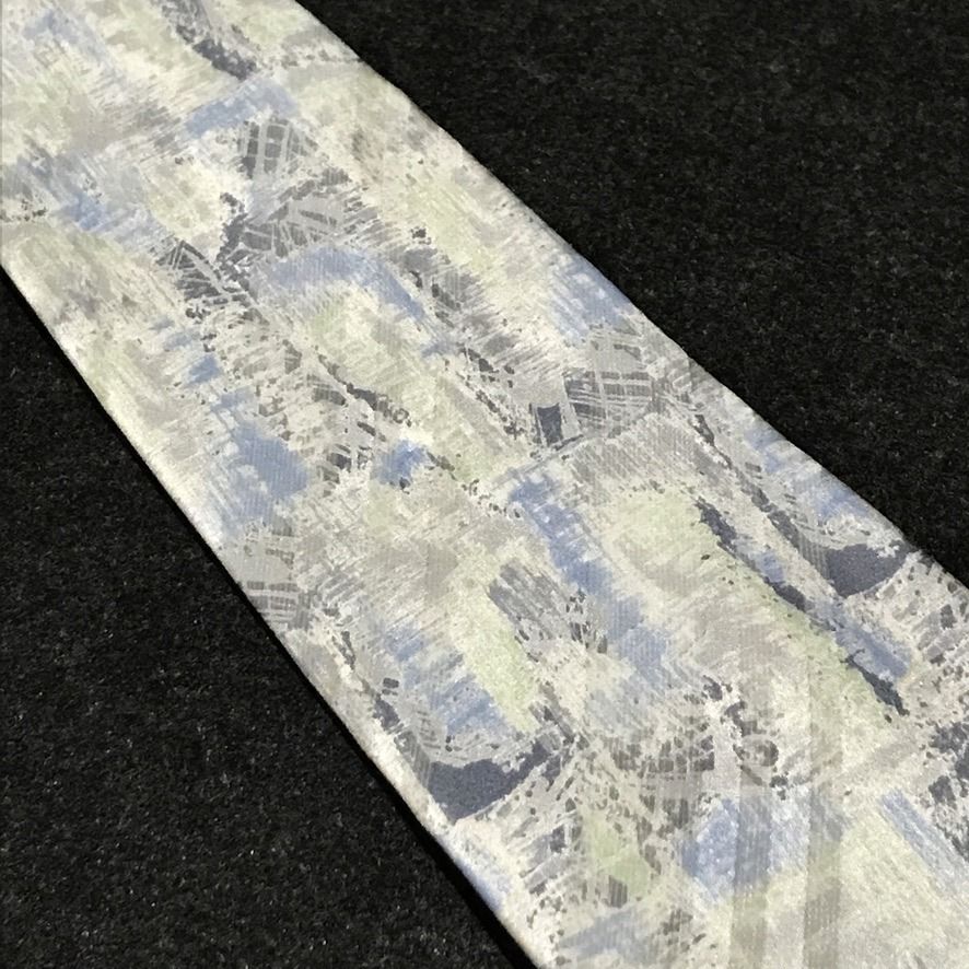 Remizio NWT Abstract Pattern Neck Tie (Category: Ties) located in Taguig. Submitted by retrogaze (Listing ID 1470595647, Image 3). Description: This 100% silk necktie by Remizio features an off-white cream base with a subtle satin luster, decorated with an artistic abstract watercolor print. The design incorporates broad diagonal shadow bands overlaid with painterly brushstrokes, cross-hatching, and textured splashes in muted sky blue, sage green