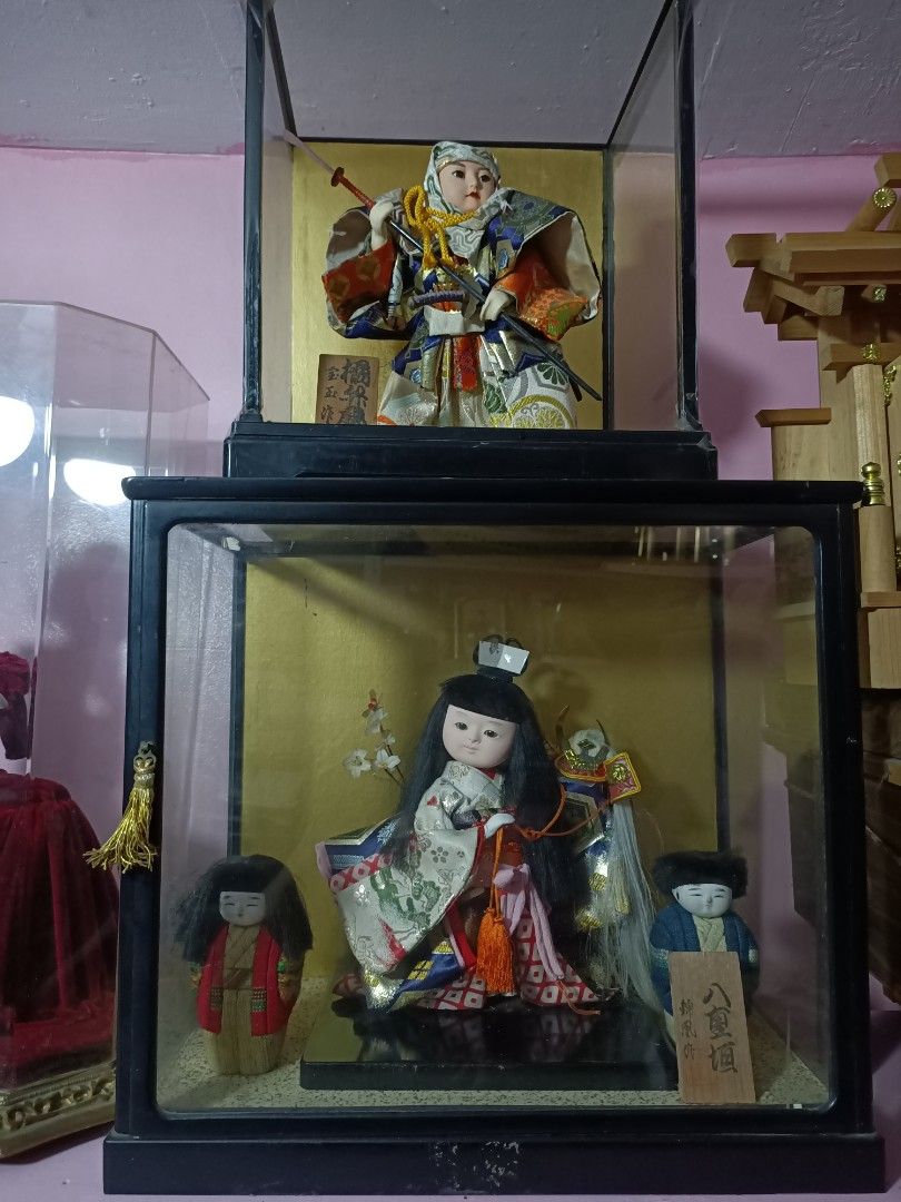 Ribbon Chic Figurine Clock with Glass Case (Category: Clocks) located in Taguig. Submitted by grandfish_55ab5c (Listing ID 1470568930, Image 2). Description: - Elegant decorative clock with a seated female figurine in a striking red velvet dress - Encased in a stylish tall hexagonal glass display case with a luxurious gold-toned base and trim - Features a classic Roman numeral clock face mounted on an ornate pillar structure - Perfect unique coll