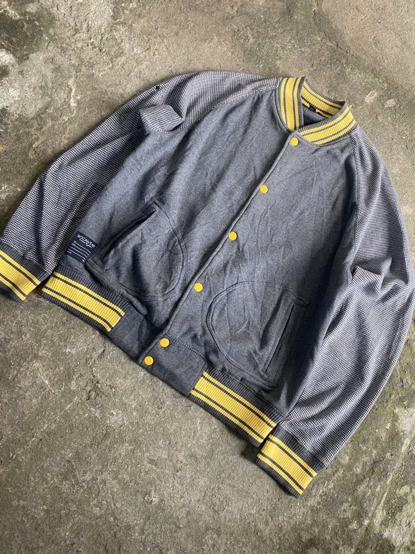 Rocawear Varsity Jacket Grey Houndstooth Sleeves Yellow Ribbing (Category: Coats, Jackets and Outerwear) located in Caloocan City. Submitted by remythrift (Listing ID 1470589868, Image 2). Description: - Brand: Rocawear - Style: Varsity jacket / Streetwear layer - Color: Dark grey with houndstooth patterned sleeves - Details: Yellow and grey striped ribbing (collar, cuffs, hem), front snap button closure, dual side pockets, signature Rocawear tag