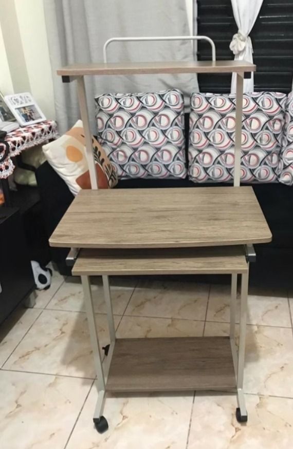 Rolling computer desk with shelves and keyboard tray (Category: Office Furniture & Fixtures) located in Roxas City. Submitted by demalatagiboy (Listing ID 1470620697, Image 1). Description: - Multi-tier mobile workstation ideal for study spaces or desktop setups - Chic wood-grain finish paired with a durable white metal frame - Convenient pull-out keyboard tray beneath the main desktop - Top shelf designed for monitors or desk accessories - Botto
