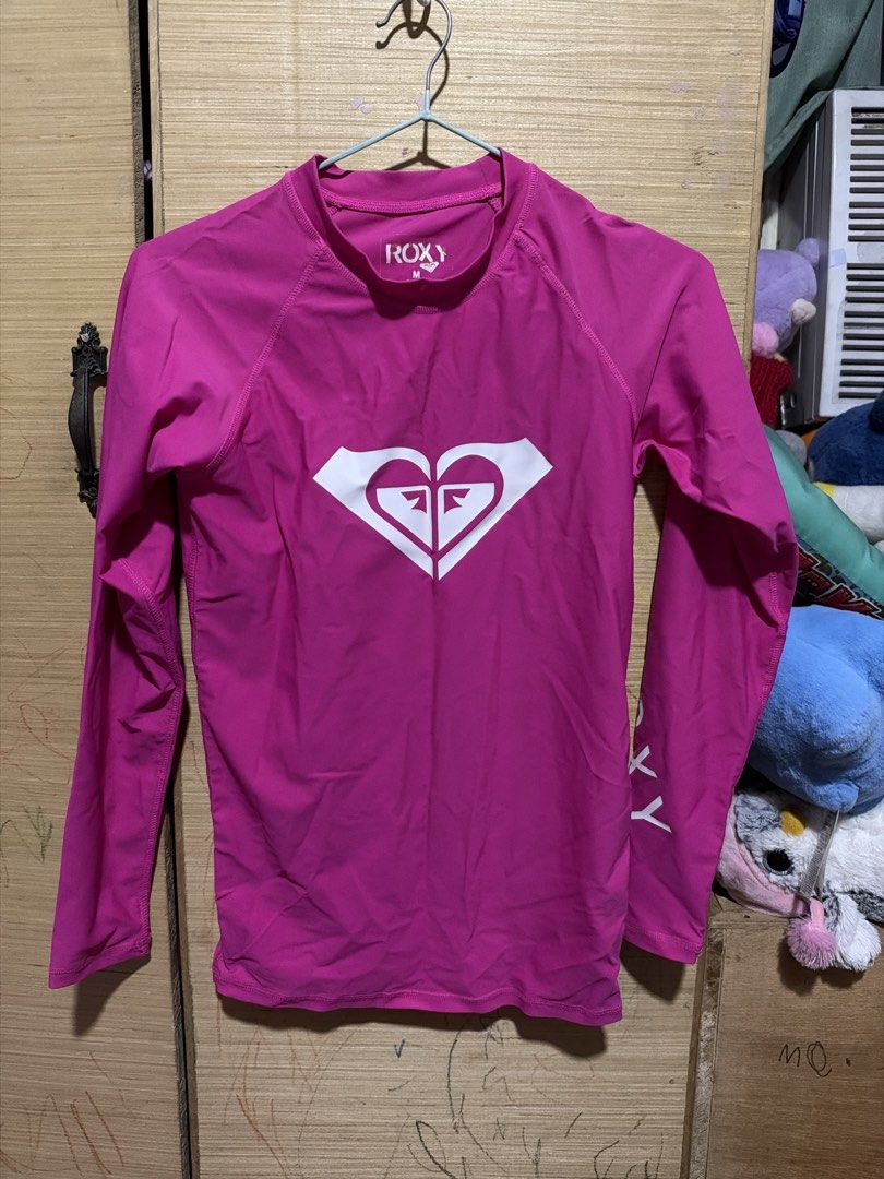 ROXY Pink Long Sleeve Rash Guard Size M (Category: Rash guard) located in Manila. Submitted by annabananna (Listing ID 1470681650, Image 1). Description: - Brand: ROXY - Size: Medium - Color: Bright Pink - Style: Long-sleeve rash guard with crew neckline - Design: Large white heart logo on chest and ROXY text on left sleeve - Material: Smooth, stretchable athletic fabric - Ideal for: Surfing, swimming, and sun protection.