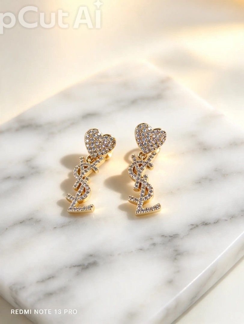 Saint Laurent YSL Crystal Heart Earrings (Category: Earrings) located in Naguilian. Submitted by jhoyukay (Listing ID 1470687429, Image 2). Description: - Authentic Saint Laurent dangling earrings - Stunning gold-tone hardware with sparkling crystal pavé - Heart-shaped stud top with dangling YSL monogram logo - Secure post-back closure - Style code 669087Y3695 - Brand new with original store tag attached.