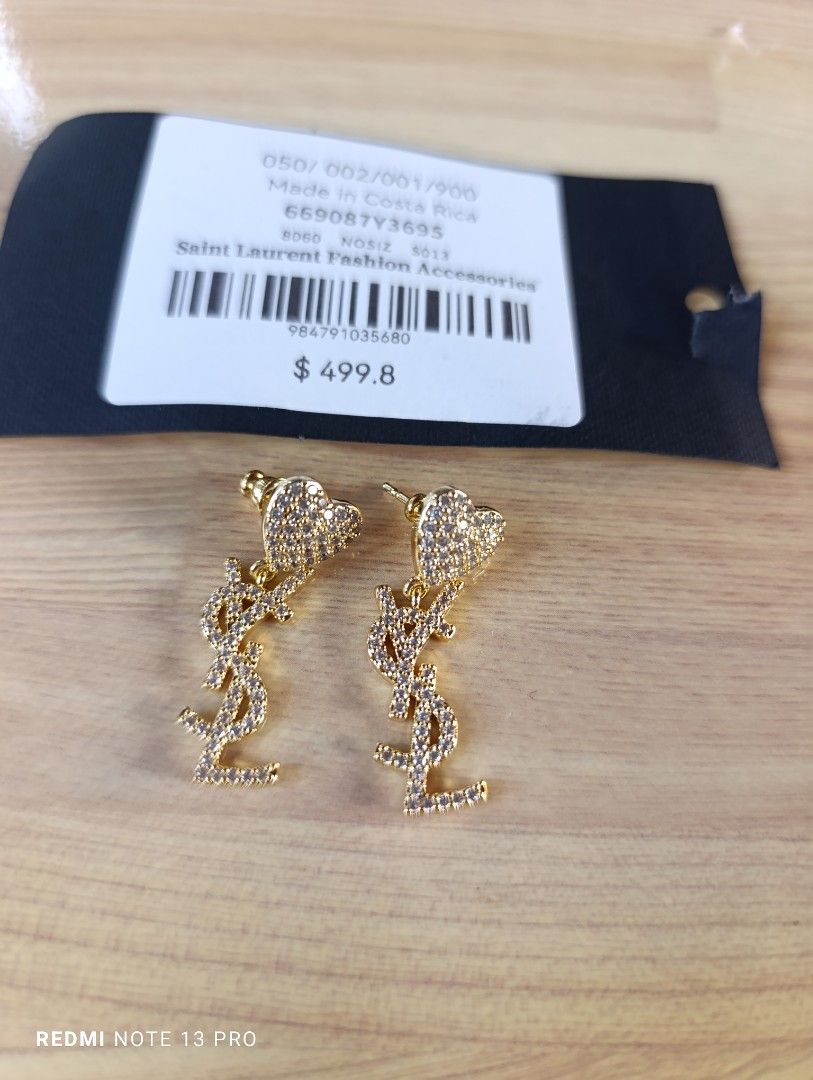Saint Laurent YSL Crystal Heart Earrings (Category: Earrings) located in Naguilian. Submitted by jhoyukay (Listing ID 1470687429, Image 1). Description: - Authentic Saint Laurent dangling earrings - Stunning gold-tone hardware with sparkling crystal pavé - Heart-shaped stud top with dangling YSL monogram logo - Secure post-back closure - Style code 669087Y3695 - Brand new with original store tag attached.