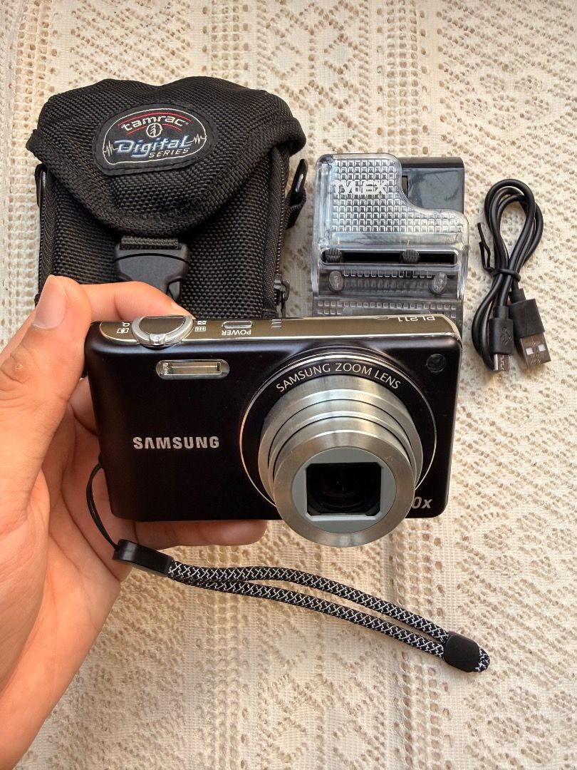 Samsung PL211 10x Zoom Digital Camera Bundle (Category: Cameras) located in Dagupan City. Submitted by digicambyharley_jmnz404 (Listing ID 1470629044, Image 2). Description: - Model: Samsung PL211 Digital Camera (Black) - Resolution: 14 Megapixels with 10x Optical Zoom - Condition: Tested, powers on, and screen is clear - Includes: Tamrac padded camera bag, battery charger, and USB cable, SD card - Extras: Wrist strap attached - Perfect for: Casu
