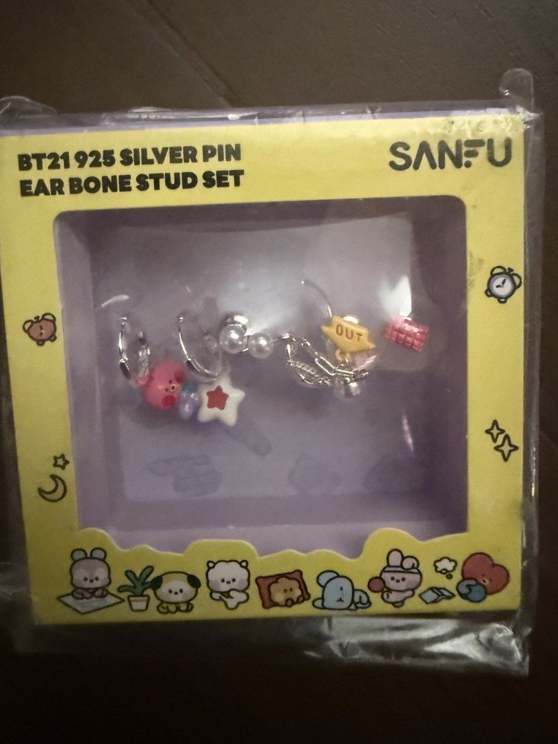 Sanfu Tata BT21 925 Silver Pin Ear Bone Stud Set (Category: K-Wave Merchandise) located in Marikina City. Submitted by culose (Listing ID 1470587597, Image 1). Description: - Official BT21 Sanfu collaboration - Material: 925 silver pin ear bone studs - Design: Multiple cute character designs with dangling charms, stars, and pearls - Packaging: Comes in a cute yellow box with graphic illustrations - Condition: Brand new, still sealed in the origin