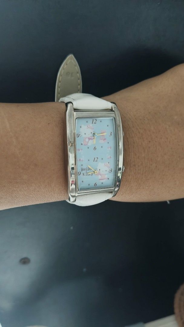 Sanrio Hello Kitty Dual Time Rectangular Watch (Category: Women's Watches) located in Taguig. Submitted by mercyeugen28914 (Listing ID 1470683338, Image 2). Description: - Brand: Sanrio Kitty - Year: 1976, 2006 - Movement: Japan movement, dual time zones with two crowns - Case: Rectangular silver-tone with light blue graphic dial - Strap: White genuine leather with croc-embossing - Condition: Water resistant; light scratches on back casing from n