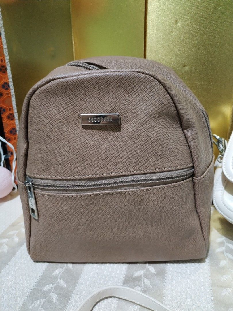 Secosana brown backpack and white cat sling bag (Category: Backpacks) located in La Trinidad. Submitted by malditas (Listing ID 1470705989, Image 3). Description: - 2-in-1 bag bundle in clean, ready-to-use condition - Secosana brown backpack featuring a handy front zipper pocket and metallic logo plate - White sling bag adorned with an adorable embroidered cat face and paw prints on the flap - Sling bag comes with an adjustable strap for comforta