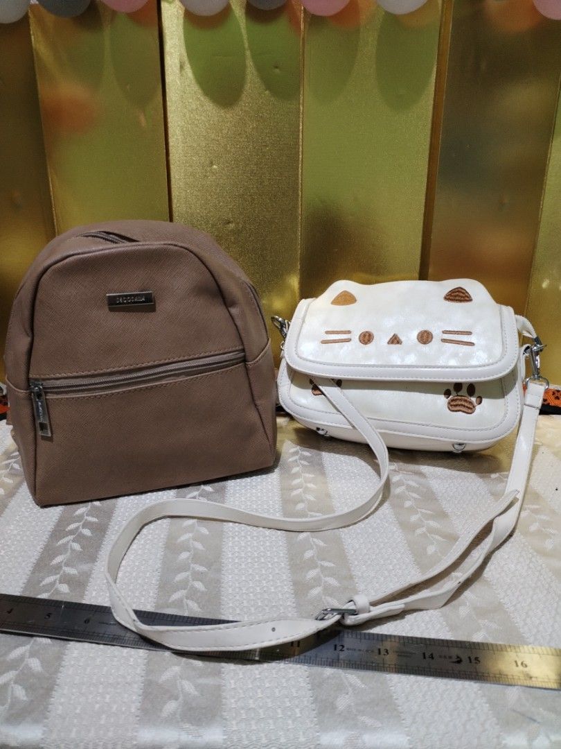Secosana brown backpack and white cat sling bag (Category: Backpacks) located in La Trinidad. Submitted by malditas (Listing ID 1470705989, Image 1). Description: - 2-in-1 bag bundle in clean, ready-to-use condition - Secosana brown backpack featuring a handy front zipper pocket and metallic logo plate - White sling bag adorned with an adorable embroidered cat face and paw prints on the flap - Sling bag comes with an adjustable strap for comforta