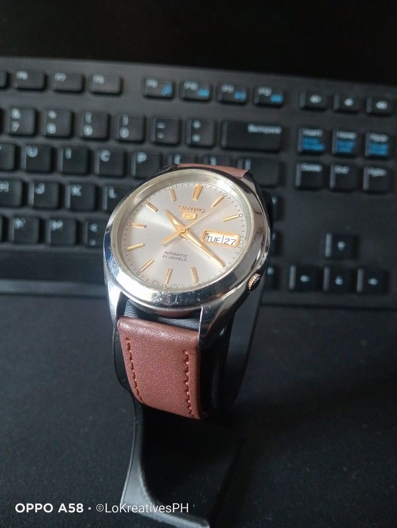 Seiko 5 SNKL19K1 (Category: Men's Watches) located in Cavite. Submitted by purpose_served (Listing ID 1470558883, Image 1). Description: Seiko 5 Automatic SNKL19K1 features a gray/silver sunburst dial with gold-tone indices and hands, a day-date display, a 21-jewel 7S26 automatic movement, Hardlex crystal, approximately 40-hour power reserve, 30-meter water resistance. Things to know: New aftermarket brown leather strap. Never opened or serviced.