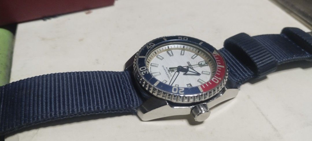 Seiko Automatic Diver's 200m Watch Pepsi Bezel (Category: Jewelry) located in Manila. Submitted by olxph_410657706 (Listing ID 1470714837, Image 1). Description: - Brand/Model: Seiko Automatic Diver Watch - Dial: White textured dial with a blue and red Pepsi bezel - Movement: Automatic movement with transparent case back - Strap: Blue nylon fabric strap with signed buckle - Condition: Stainless steel case has minor hairline scratches; keeps time 