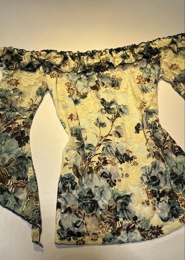 ShalyShow Off-Shoulder Floral Lace Top (Category: Blouses) located in Bacolod City. Submitted by thlnn_vls (Listing ID 1470702693, Image 2). Description: - Brand: Shaly - Style: Off-shoulder slim-fit top - Material: Stretchy mesh lace - Color/Print: Pale yellow with dark green and brown floral print - Details: Ruffled neckline and long bell sleeves with lettuce hem trim.
