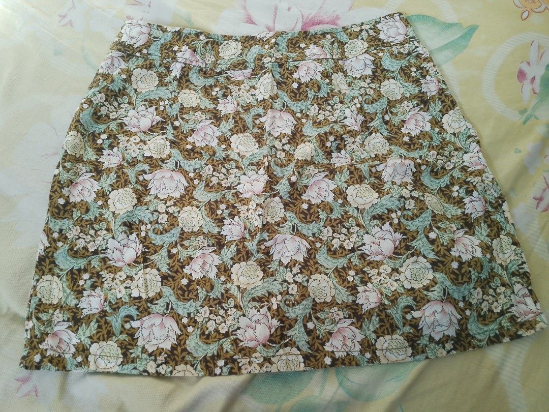 SHAPES Floral Mini Skirt Size M (Category: Skirts) located in Valenzuela. Submitted by kn.sell (Listing ID 1470615773, Image 1). Description: - Brand/Style: Shapes short floral skirt - Size: Medium - Design: Brown background with pink/cream flowers and green leaves - Details: Back zipper closure, pleated section near the back hem - Fabric: Lightweight and comfortable, easy to pair with basic tops - Condition: Clean interior lining and clear tag.