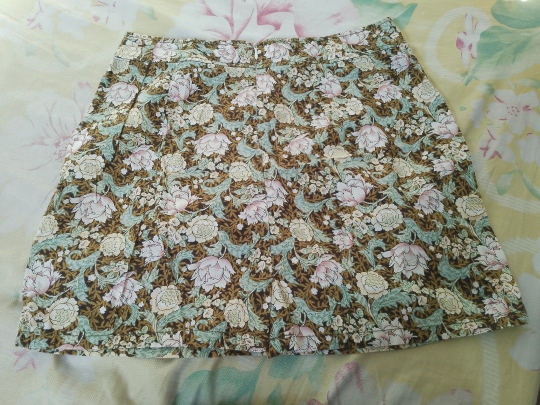 SHAPES Floral Mini Skirt Size M (Category: Skirts) located in Valenzuela. Submitted by kn.sell (Listing ID 1470615773, Image 2). Description: - Brand/Style: Shapes short floral skirt - Size: Medium - Design: Brown background with pink/cream flowers and green leaves - Details: Back zipper closure, pleated section near the back hem - Fabric: Lightweight and comfortable, easy to pair with basic tops - Condition: Clean interior lining and clear tag.