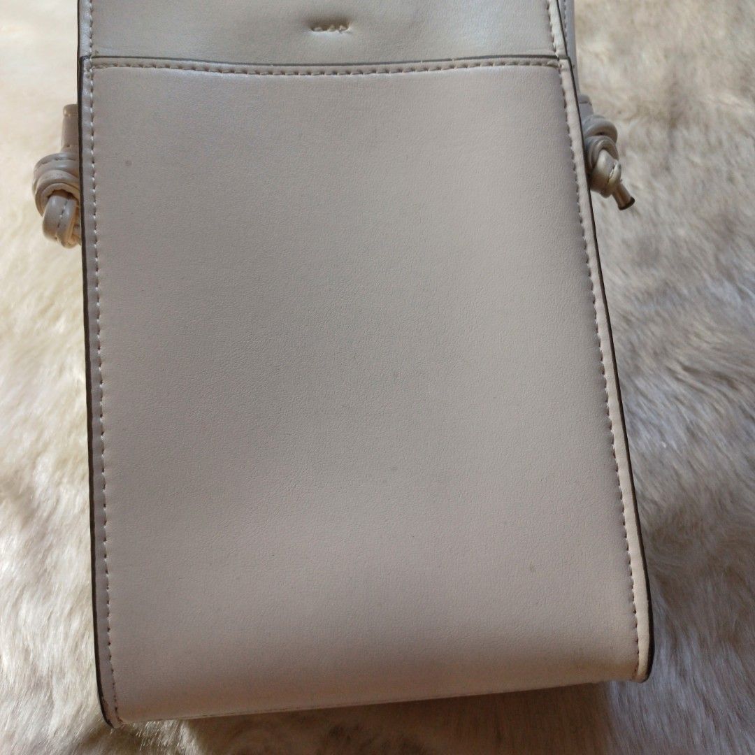 Sling bag from Uniqlo (Category: Cross-body Bags) located in Pasig City. Submitted by eden_online_shop (Listing ID 1470617938, Image 3). Description: - Color: Off white - Material: Faux leather - Design: Slim vertical profile with clean lines - Storage: Fits mobile phones and essential cards easily - Strap: Long, thin strap with stylish knotted ends - Style: Perfect match for casual everyday outfits - Condition: Well-maintained and in great shape