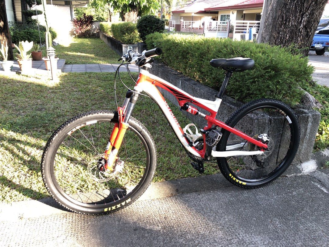 Specialized Full Suspension Mountain Bike (Category: Bicycles) located in Angeles City. Submitted by jcarlo1890 (Listing ID 1470601484, Image 2). Description: - Brand/Model: Specialized full suspension mountain bike - Color: Red and white - Suspension: Front fork and rear shock absorbers - Wheels: Maxxis tires on black rims - Brakes: Hydraulic disc brakes (front and back) - Accessories: White bottle cage, black saddle, and grips - Condition: Norm