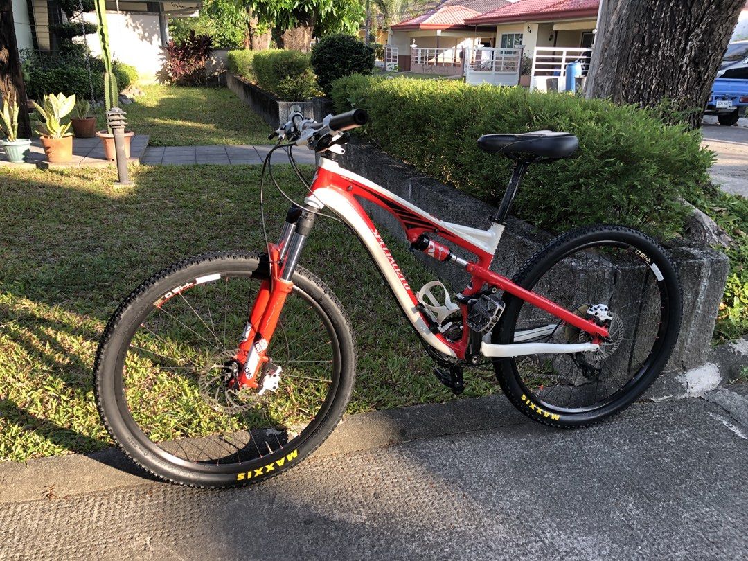 Specialized Full Suspension Mountain Bike (Category: Bicycles) located in Angeles City. Submitted by jcarlo1890 (Listing ID 1470601484, Image 1). Description: - Brand/Model: Specialized full suspension mountain bike - Color: Red and white - Suspension: Front fork and rear shock absorbers - Wheels: Maxxis tires on black rims - Brakes: Hydraulic disc brakes (front and back) - Accessories: White bottle cage, black saddle, and grips - Condition: Norm