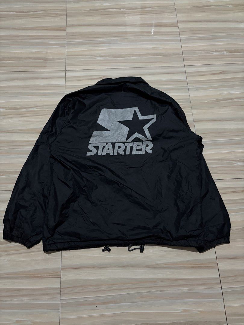Starter Vintage Black Nylon Coach Jacket Size L (Category: Coats, Jackets and Outerwear) located in Ajuy. Submitted by reeyn0515 (Listing ID 1470708588, Image 2). Description: -25x29 - Brand: Starter Corp - Color: Solid black - Size: Large (L) - Design: Large embroidered logo patch on chest and oversized logo on the back - Features: Snap button front, collar, and adjustable drawstring hem - Lining: Grey jersey cotton lining for added warmth.