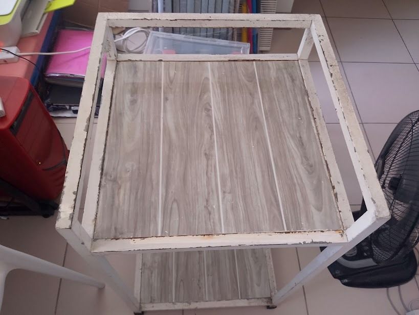 Stove Table Single (Category: Shelves, Cabinets & Racks) located in Quezon City. Submitted by susmaryosep1 (Listing ID 1470670428, Image 3). Description: Stove Table Single - 2-tier utility cart with smooth-rolling wheels - White metal frame with visible wear and chipped paint on edges - Greyish brown wooden laminate shelves - Top shelf features a protective metal railing - Bottom shelf offers spacious extra storage - Sturdy, heavy-duty construct