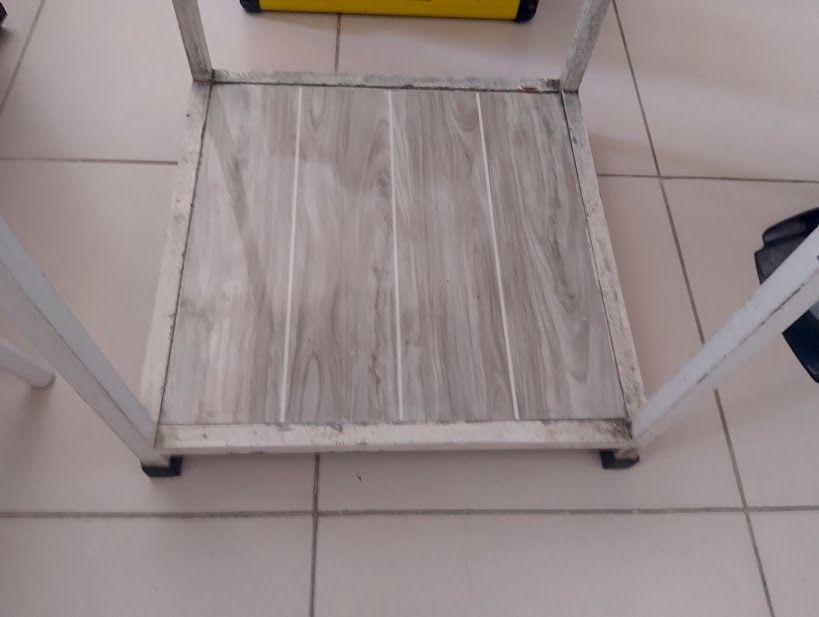 Stove Table Single (Category: Shelves, Cabinets & Racks) located in Quezon City. Submitted by susmaryosep1 (Listing ID 1470670428, Image 2). Description: Stove Table Single - 2-tier utility cart with smooth-rolling wheels - White metal frame with visible wear and chipped paint on edges - Greyish brown wooden laminate shelves - Top shelf features a protective metal railing - Bottom shelf offers spacious extra storage - Sturdy, heavy-duty construct
