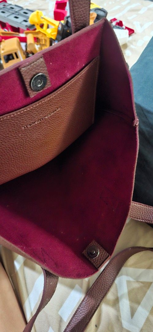 Straightforward Brown Leather Tote Bag (Category: Tote Bags) located in Paranaque City. Submitted by finders_thriftersph (Listing ID 1470675180, Image 2). Description: - Material: Premium brown pebbled leather with deep maroon suede interior - Straps: Comfortable dual shoulder straps with clean stitching - Closure: Secure magnetic main snap closure - Storage: Convenient inner pocket with magnetic button closure - Style: Simple, structured design 