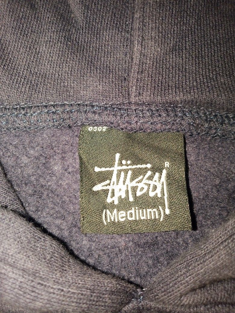 Stussy Dark Navy Hoodie Size Medium (Category: Coats, Jackets and Outerwear) located in Allen. Submitted by milyonaryung_gipit (Listing ID 1470567284, Image 2). Description: - Brand: Stussy - Size: Medium - Color: Dark Navy - Material: 80% Cotton, 20% Polyester (Made in China) - Features: Large embroidered signature chest logo, front kangaroo pocket, adjustable drawstring hood, ribbed cuffs and hem - Condition: Shows slight fading from washing, w