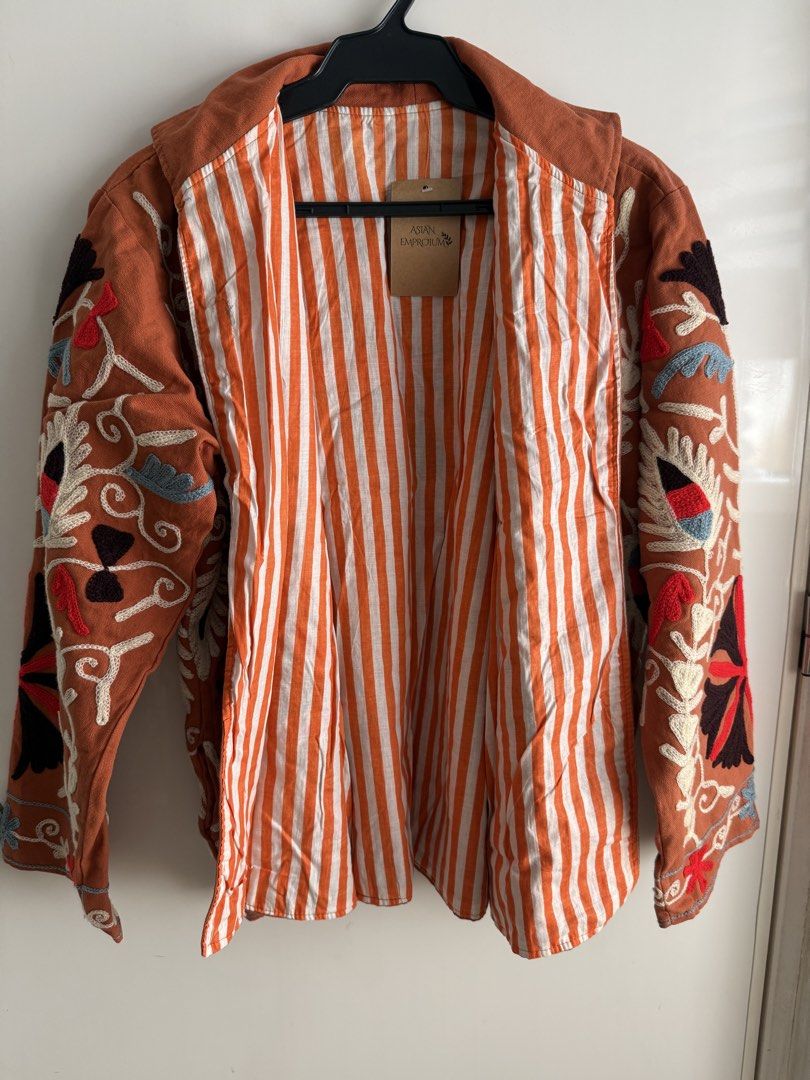 Suzani Jacket Cotton Embroidered Rust Color reversible (Category: Coats, Jackets and Outerwear) located in Las Pinas. Submitted by katrt (Listing ID 1470596445, Image 3). Description: - Brand: Asian Emporium - Condition: Brand new with tags attached - Color: Rust orange with striking white, black, red, and blue floral embroidery - Design: Open front style with a chic high collar and striped inner lining - Measurements: ~23 inches pit to pit, ~25 
