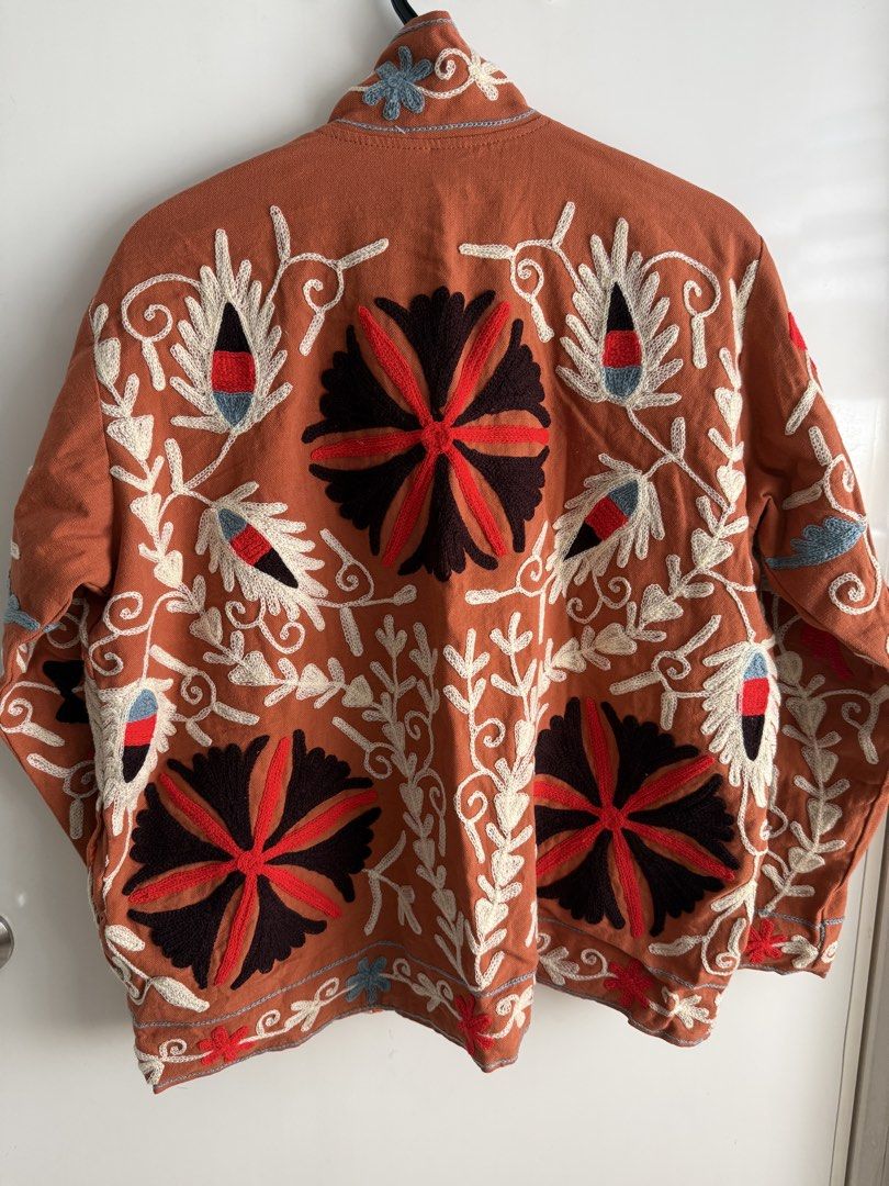 Suzani Jacket Cotton Embroidered Rust Color reversible (Category: Coats, Jackets and Outerwear) located in Las Pinas. Submitted by katrt (Listing ID 1470596445, Image 2). Description: - Brand: Asian Emporium - Condition: Brand new with tags attached - Color: Rust orange with striking white, black, red, and blue floral embroidery - Design: Open front style with a chic high collar and striped inner lining - Measurements: ~23 inches pit to pit, ~25 