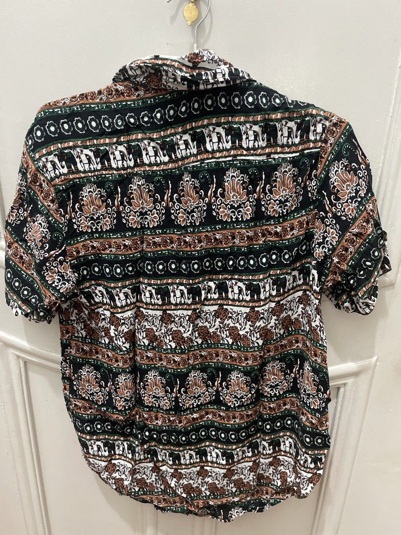 Thai Vintage style patterned short sleeve button-up shirt (Category: Tshirts & Polo Shirts ) located in Cainta. Submitted by nancygoreng (Listing ID 1470624431, Image 2). Description: - Size: Medium - Design: Intricate alternating horizontal bands of elephants, florals, and geometric motifs, from Thailand - Colors: Black base with green, white, and brown details - Features: Standard collar, front button closure, lightweight fabric - Perfect for: 