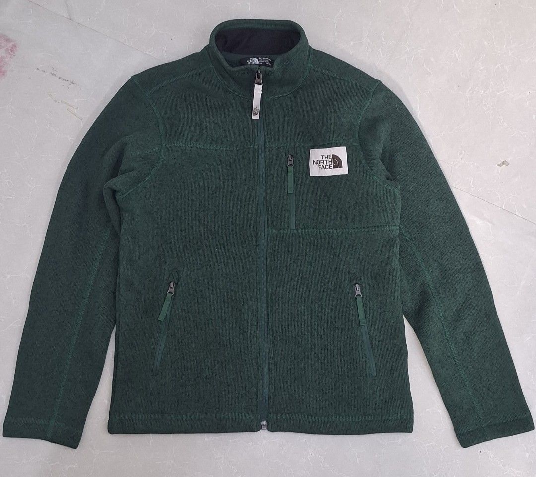 The North Face Green Fleece Jacket (Category: Babies & Kids Fashion) located in Pasay City. Submitted by al1son18 (Listing ID 1470603567, Image 1). Description: - Brand: The North Face - Style: Full-zip fleece jacket with high collar - Color: Dark Green Heather - Storage: 3 functional zipped front pockets - Branding: Classic square TNF logo patch on left chest - Material: Thick, heavy-duty fleece for maximum warmth - Condition: Excellent, clean c