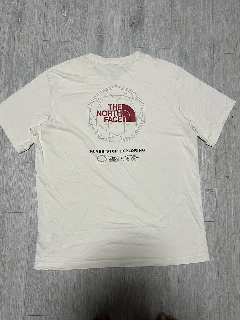 The North Face Never Stop Exploring Graphic T-Shirt (Category: Tshirts & Polo Shirts ) located in Manila. Submitted by jorgemabelin2001 (Listing ID 1470697955, Image 2). Description: - Brand: The North Face - Color: Off-white - Material: 100% Cotton - Design: Small red chest logo, large geometric tent graphic and 'Never Stop Exploring' text on the back - Size: Men US L / Asia XL | Women US XL / Asia 2XL - Made in: China - Flaws: Noticeable yellow