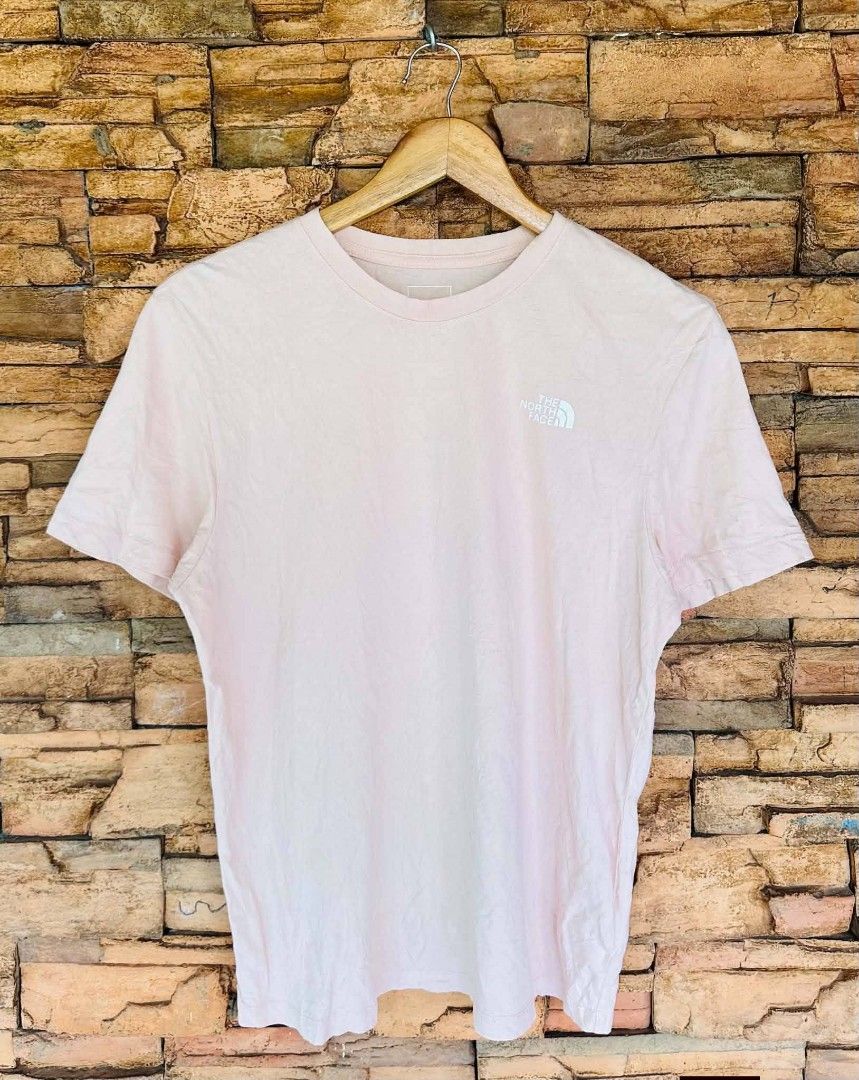The North Face Pink T-Shirt (Category: Activewear) located in Santiago. Submitted by reyibanez253969 (Listing ID 1470702695, Image 1). Description: - Authentic The North Face pink t-shirt - Size: S-M - 19x26 - Short sleeves with a classic crew neck - Small white logo printed on the left chest - Large back graphic with mountain artwork and 'Never Stop Exploring' phrase - Includes holographic authenticity tag inside the collar - Comfortable regular