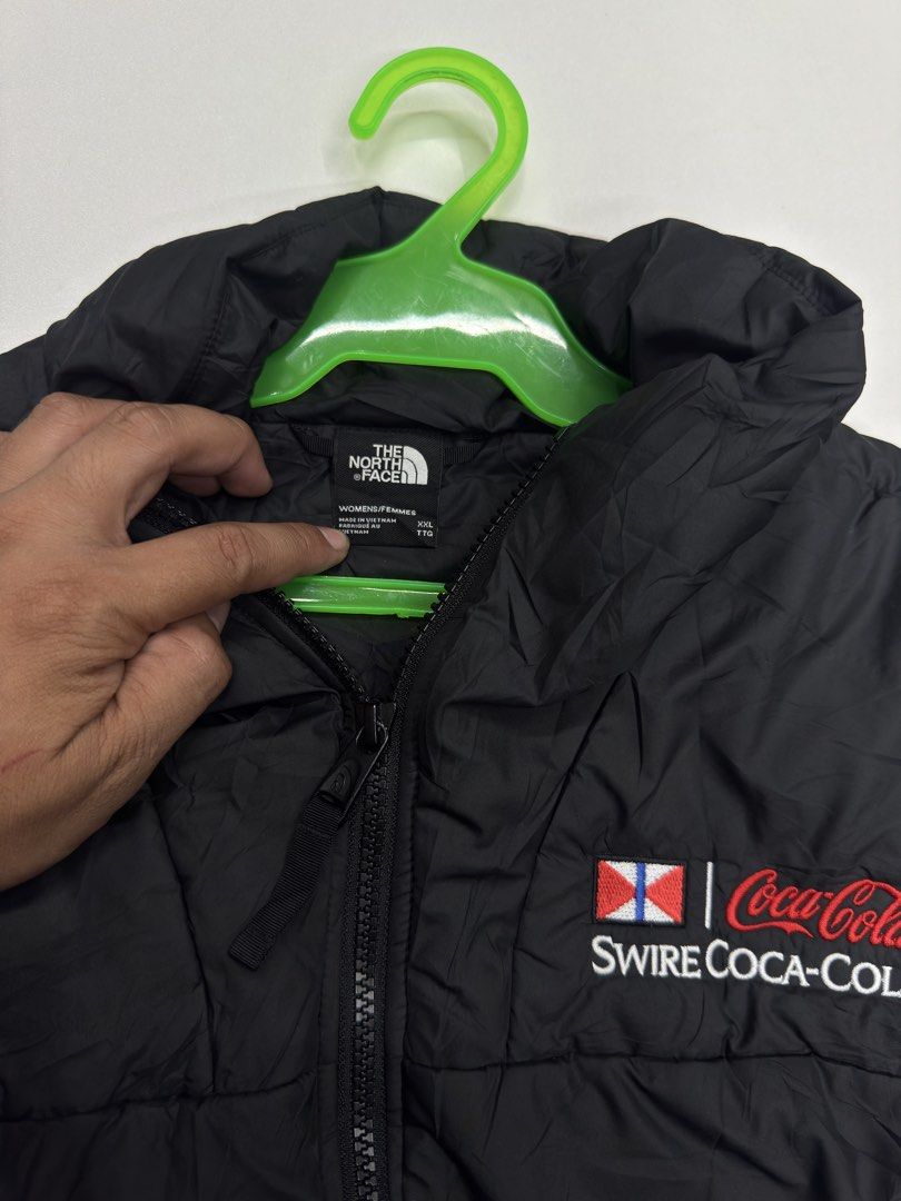 The North Face x Swire Coca-Cola Puffer Jacket (Category: Coats, Jackets and Outerwear) located in Bustos. Submitted by thenlnclot60500 (Listing ID 1470639979, Image 3). Description: - Brand: The North Face - Style: Lightweight quilted puffer jacket with stand collar and full zip front - Color: Black - Size: Women's XXL - Material: 100% polyester (shell, lining, filling) - Special Feature: Swire Coca-Cola embroidery on the chest - Condition: Clea