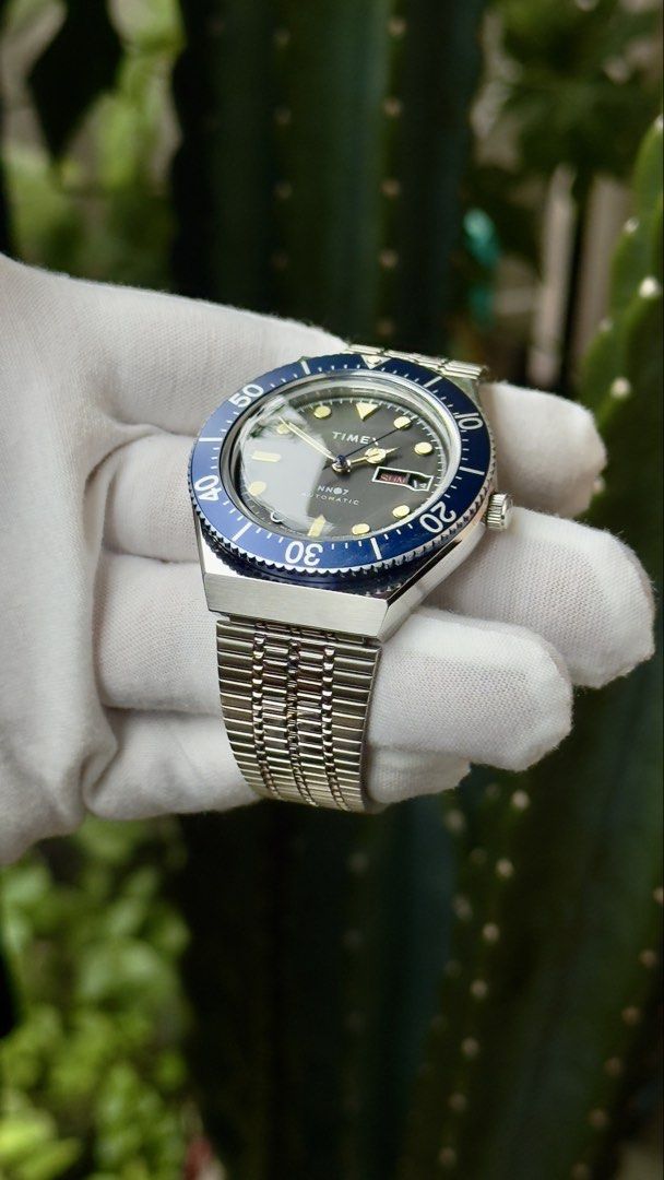 Timex NN07 Automatic Blue Bezel Watch BATMAN (Category: Men's Watches) located in Manila. Submitted by junjun12356 (Listing ID 1470557825, Image 2). Description: - Brand/Collab: Timex x NN07 Automatic Watch - Dial: Dark dial with day and date window at 3 o'clock - Bezel: Blue rotating bezel with white markers - Strap: Steel bracelet with adjustable clasp and 'T' logo crown - Condition: Worn a few times, minimal signs of wear on case and bracelet.