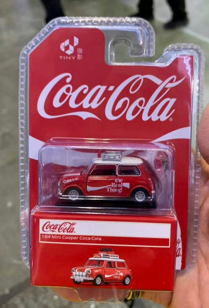 Tiny EXCLUSIVE! 1:64 Mini Cooper Coca-Cola Diecast Model Car (Category: Vehicle & Diecast Models) located in Tagaytay City. Submitted by gracey332 (Listing ID 1470672170, Image 2). Description: - Brand: Tiny - Scale: 1:64 - Model: Mini Cooper with Coca-Cola livery ("The Real Thing!" branding) - Colorway: Red body with white roof and roof rack - Condition: Brand new, unopened blister packaging inside a red display box - Ideal for die-cast collecto