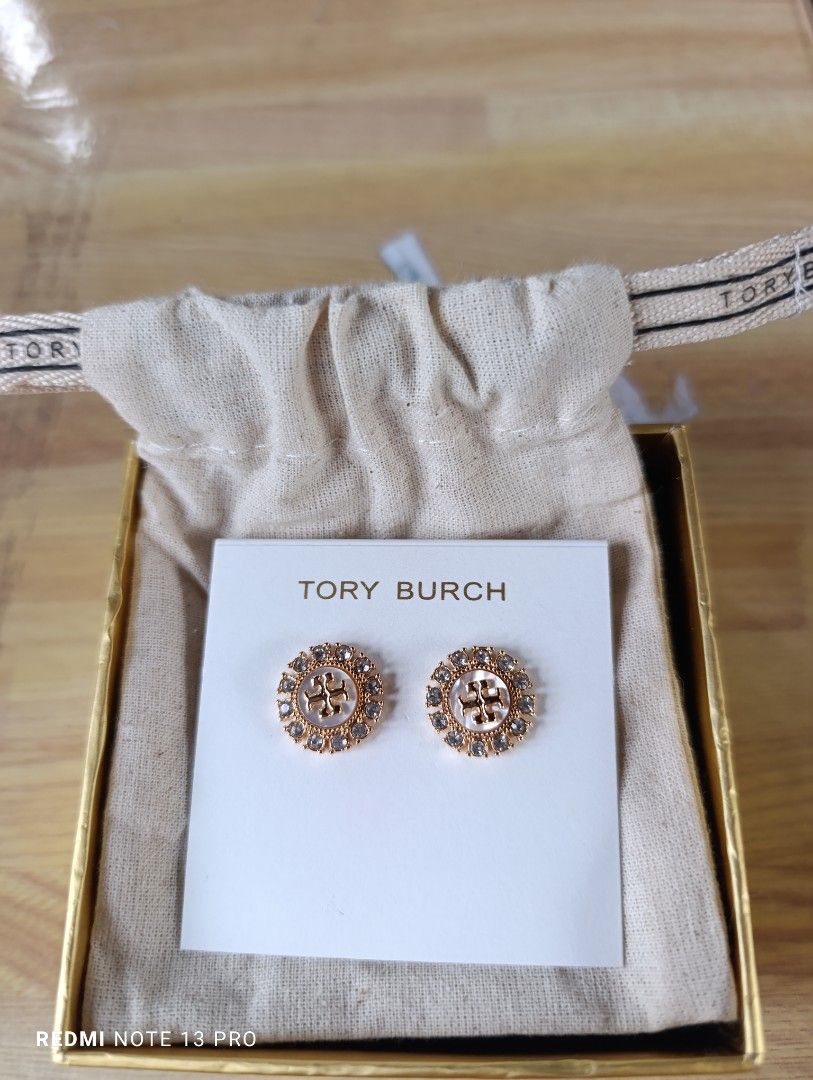 Authenthic 💯 Tory Burch Crystal Logo Stud Earrings (Category: Earrings) located in Naguilian. Submitted by jhoyukay (Listing ID 1470687579, Image 2). Description: - Authentic Tory Burch gold-tone stud earrings - Features a chic pearlized center surrounded by a sparkling crystal halo - Iconic Double T logo right in the middle - Condition: Brand new, never worn, still pinned to the original paper card - Inclusions: Comes with a branded dust bag an