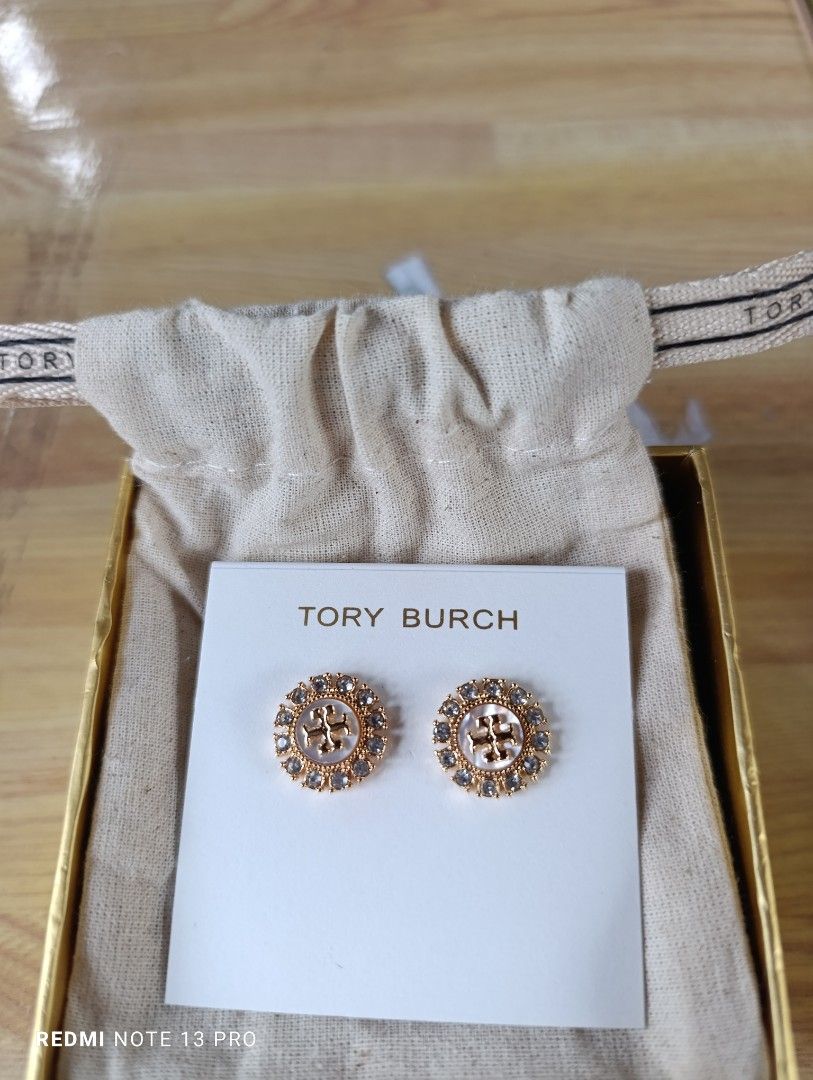 Authenthic 💯 Tory Burch Crystal Logo Stud Earrings (Category: Earrings) located in Naguilian. Submitted by jhoyukay (Listing ID 1470687579, Image 3). Description: - Authentic Tory Burch gold-tone stud earrings - Features a chic pearlized center surrounded by a sparkling crystal halo - Iconic Double T logo right in the middle - Condition: Brand new, never worn, still pinned to the original paper card - Inclusions: Comes with a branded dust bag an