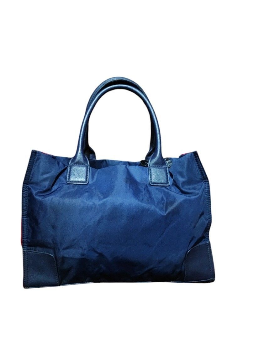 Tory Burch Medium Tote Bag - Negotiable!!! (Category: Tote Bags) located in Manila. Submitted by axelyuna.27 (Listing ID 1470574911, Image 2). Description: Authentic Tory Burch navy blue nylon tote featuring a bold red front logo patch, contrasting red side gussets, and dark blue leather handles. Includes a branded interior lining and a convenient zip pocket. Made in the Philippines..