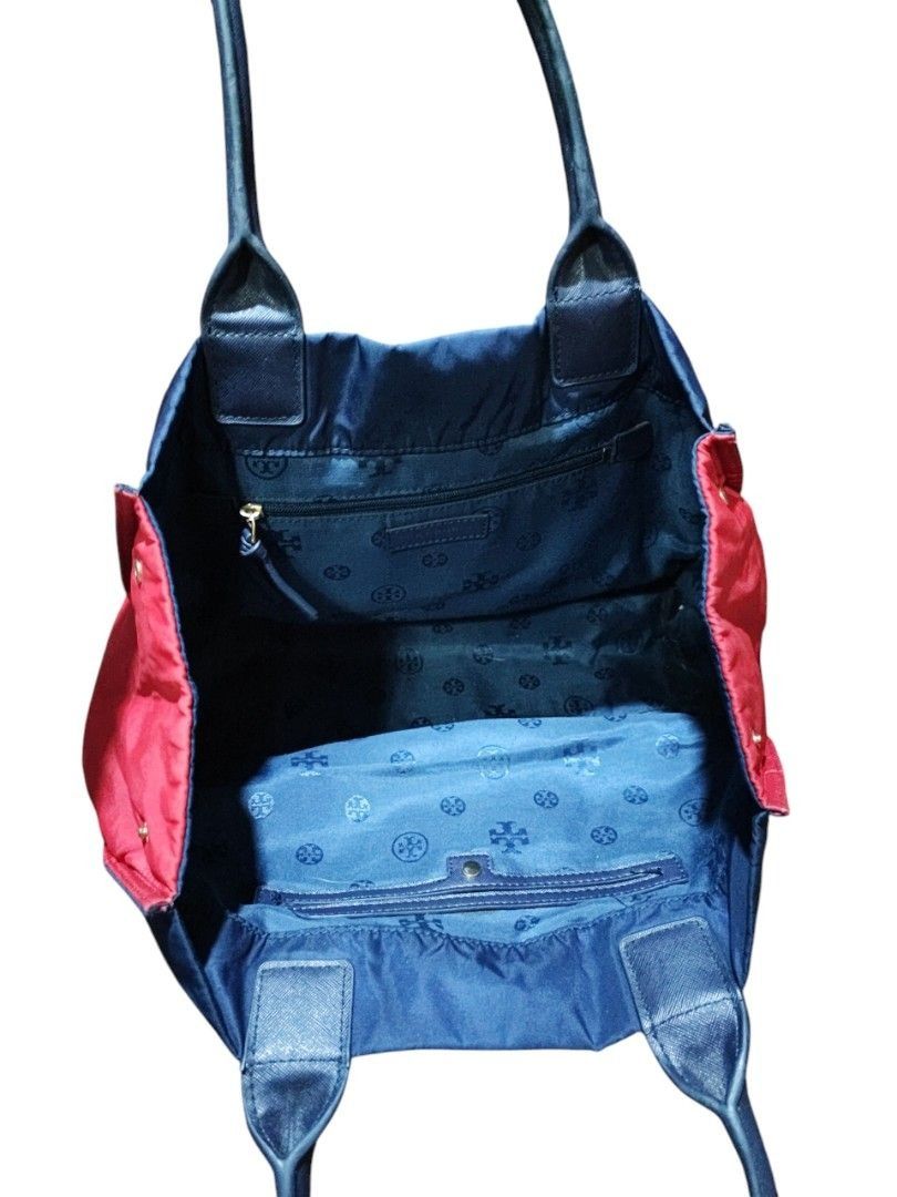 Tory Burch Medium Tote Bag - Negotiable!!! (Category: Tote Bags) located in Manila. Submitted by axelyuna.27 (Listing ID 1470574911, Image 3). Description: Authentic Tory Burch navy blue nylon tote featuring a bold red front logo patch, contrasting red side gussets, and dark blue leather handles. Includes a branded interior lining and a convenient zip pocket. Made in the Philippines..