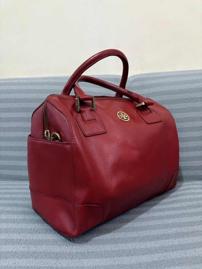Tory Burch Red Leather Satchel Handbag (Category: Luxury Bags & Wallets) located in Pasig City. Submitted by mau_llamas (Listing ID 1470670474, Image 1). Description: - Brand: Tory Burch - Style: Leather Satchel Bag - Color: Red with gold-tone hardware - Closure: Top zip closure with double top handles - Exterior: Signature logo emblem on the front, structured base with reinforced corners - Interior: Pink monogram fabric lining, 1 zip pocket, and