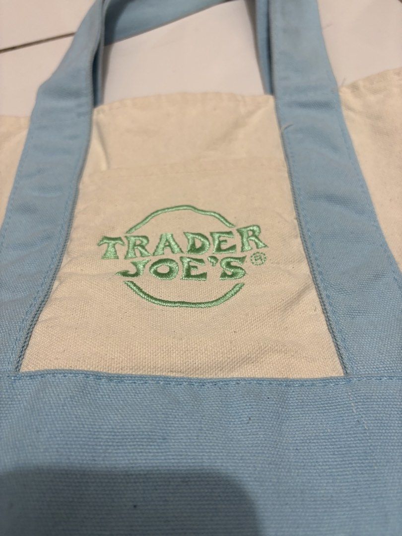 Trader Joe's mini Blue Canvas Tote Bag (Category: Tote Bags) located in Taguig. Submitted by cftbncs (Listing ID 1470560597, Image 1). Description: - Authentic Trader Joe's canvas tote bag - Colorway: Cream body with stylish light blue handles and bottom panel - Features a green embroidered Trader Joe's logo on the front pocket - Made from durable, heavy-duty cotton canvas - Equipped with sturdy double straps for comfortable carrying - Spacious s