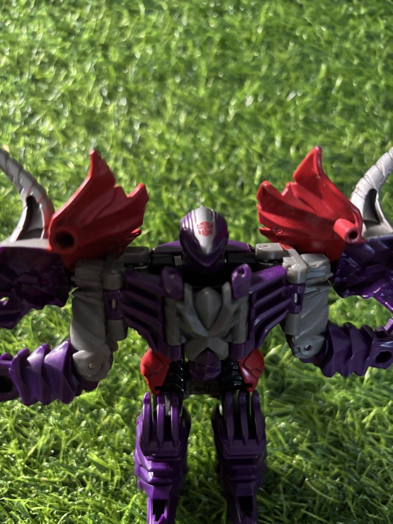 Transformers Dinobot Slug Action Figure Purple (Category: Action & Battle Toys) located in Makati City. Submitted by rare_thrift_stuff (Listing ID 1470612428, Image 2). Description: - Type: Transformers action figure - Mode: Transforms between robot and triceratops dinosaur - Color Scheme: Purple and red with silver horns and spine details - Insignia: Autobot symbol stamped on chest and dinosaur body - Condition: Clean plastic body with smooth jo