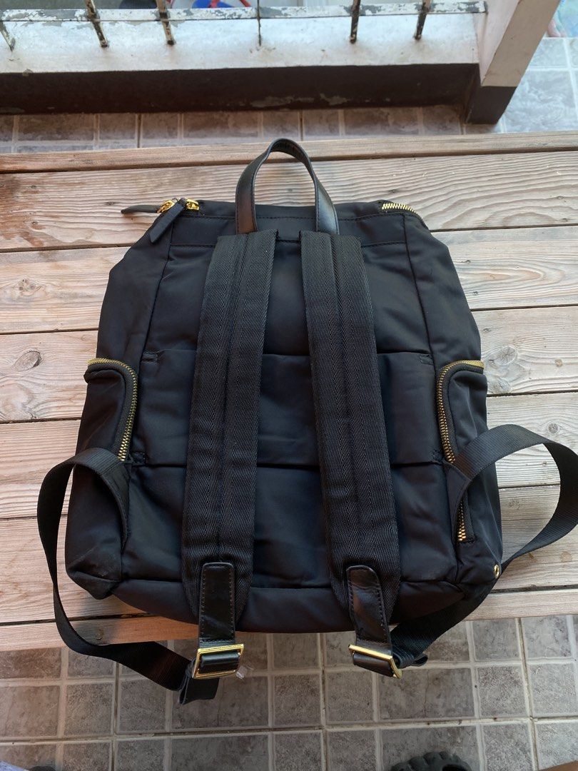 TUMI Black Nylon Backpack with Gold Hardware (Category: Backpacks) located in San Fernando. Submitted by thrifteezy6 (Listing ID 1470635424, Image 3). Description: - Authentic TUMI black nylon backpack - Elegant gold-tone zippers and hardware - Top handle and comfortable adjustable shoulder straps - Front zip pocket with stylish leather zipper pulls - Spacious main compartment with interior organization pockets (zip and slip pockets) - Light grey