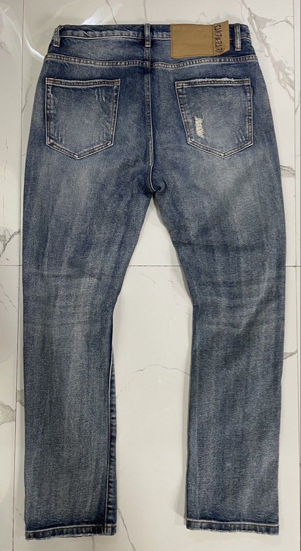 Vetemets Rhinestone Distressed Denim Jeans (Category: Jeans) located in Calapan. Submitted by lucasthrifts (Listing ID 1470569577, Image 2). Description: - Brand/Model: Vetemets Unisex Denim Jeans (Hiver 2021) - Size: 31 - Color/Wash: Mid-blue wash - Design Details: Rhinestone lettering across the front, distressed rips on both legs - Features: Standard button fly, classic five-pocket design, and paper brand patch with handwritten lettering .