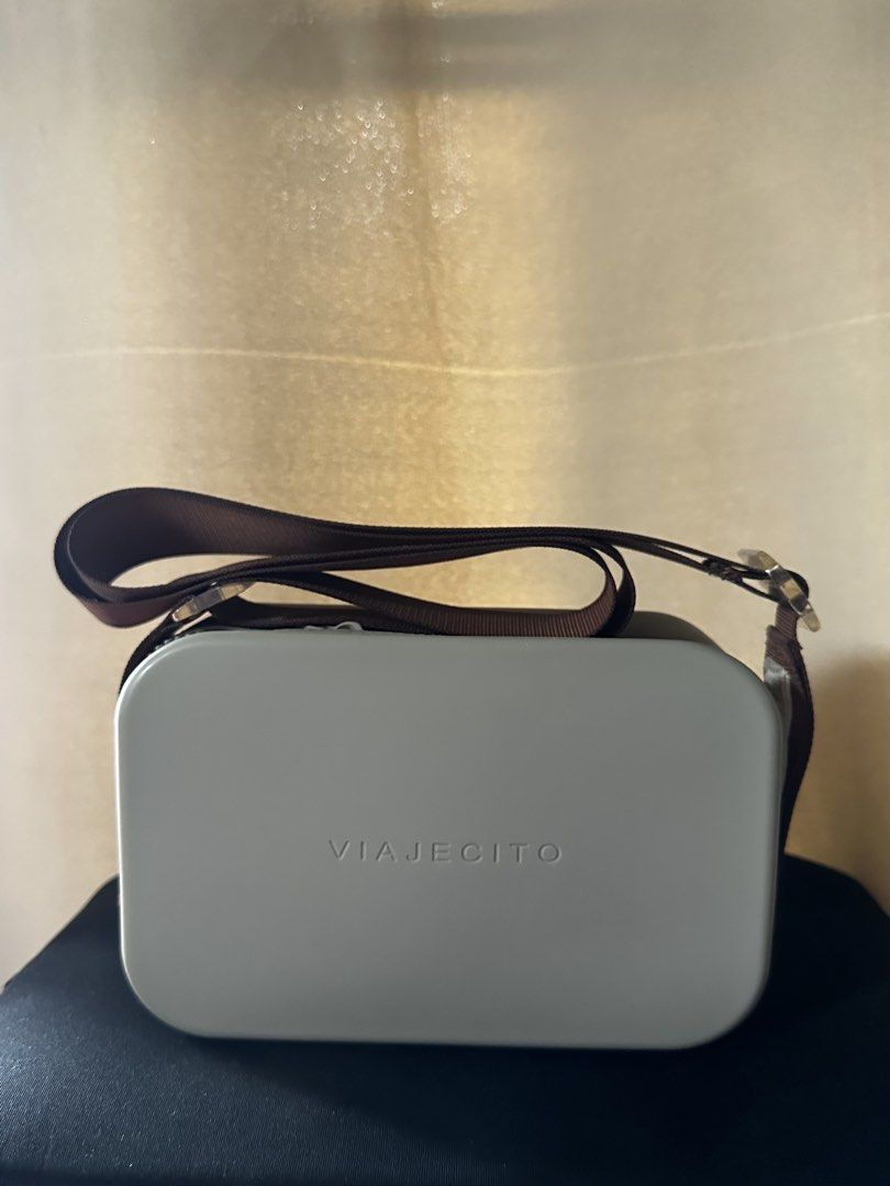 Viajecito Crossbody Bag with Brown Strap (Category: Cross-body Bags) located in Quezon City. Submitted by nclbau (Listing ID 1470563455, Image 1). Description: - Brand: Viajecito - Color: Grey hard shell with embossed front logo - Strap: Brown adjustable strap with durable metal hardware - Closure: Secure top zipper - Size: Great daily size, fits phone, keys, and wallet - Condition: Clean and structured shape.